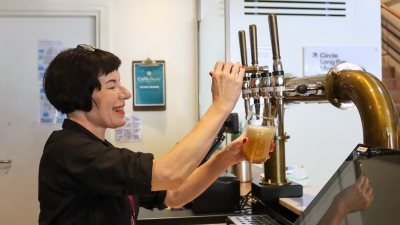 A woman with a black bob pulls a pint