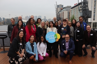 Image of a group of individuals standing around a 'We are a Living Wage employer plaque' on a yacht