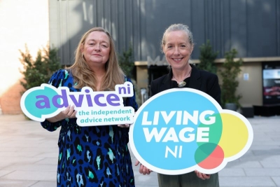 Two women holding logos from advice NI and Living Wage NI