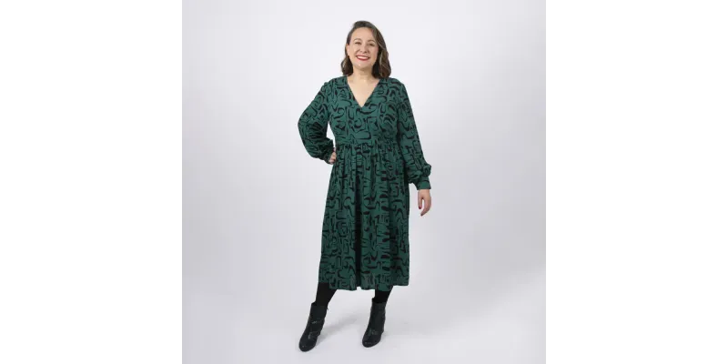 Women with green mid length dress styling a sewing pattern