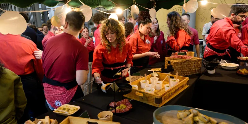 Catering staff busy preparing Asian food in red shirts and black overalls.