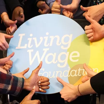 thumbs up around Living Wage sign