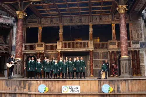 Children performing on stage at the Globe Theatre during Living Wage Week
