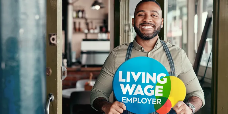 Living Wage Employer sign with man in cafe